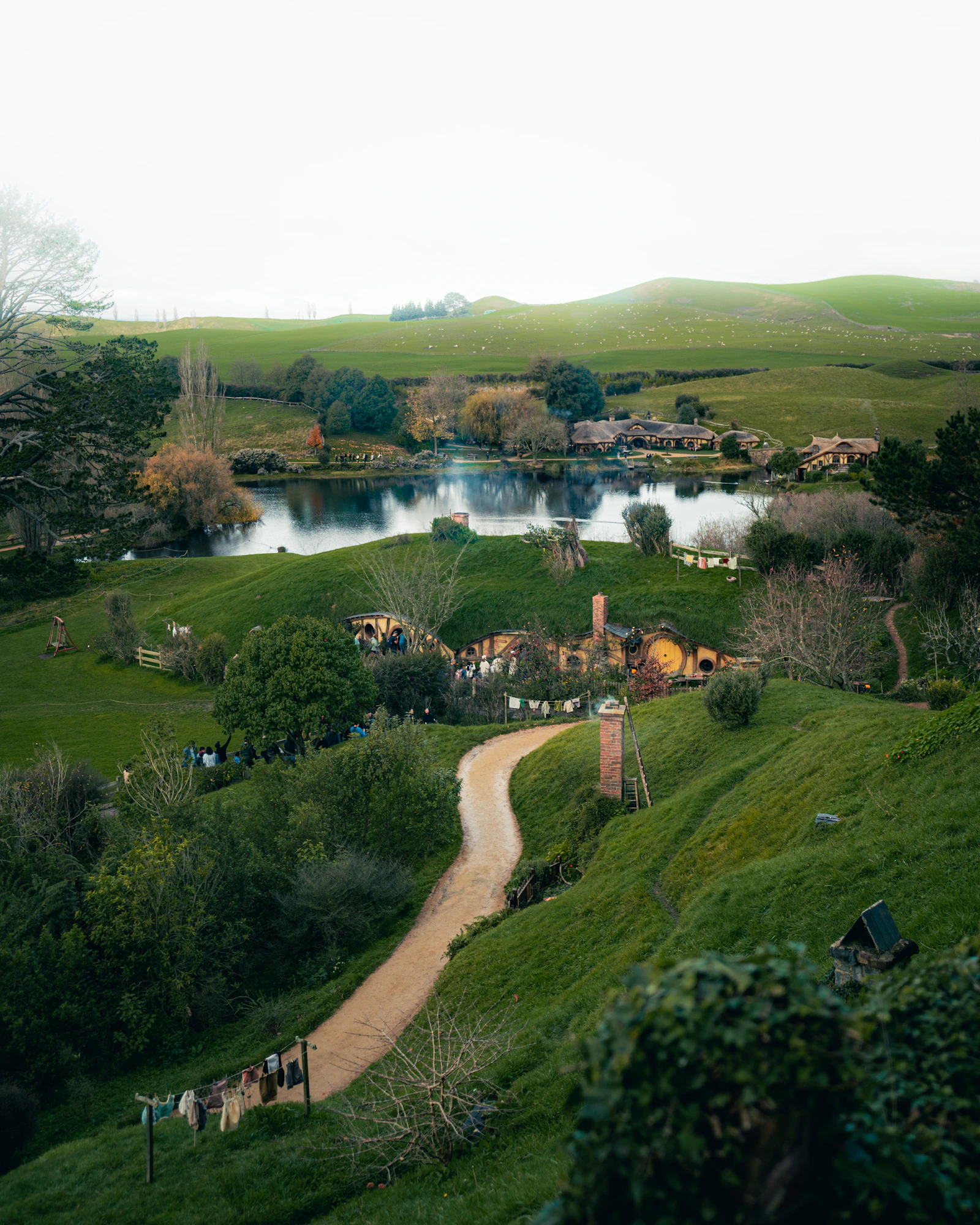 Casas de Hobbiton junto al lago y las colinas verdes de Matamata