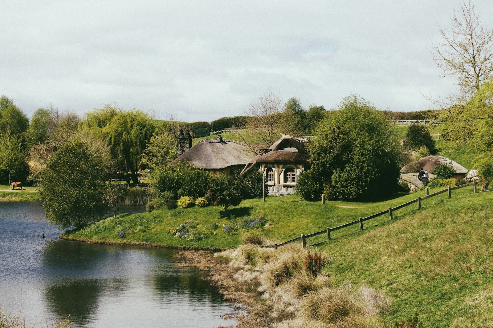 Paisaje verde y construcciones de Hobbiton junto al agua